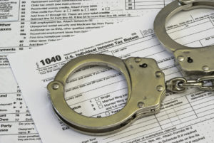 Handcuffs resting on top of tax papers. This picture symbolizes tax evasion in West Palm Beach.